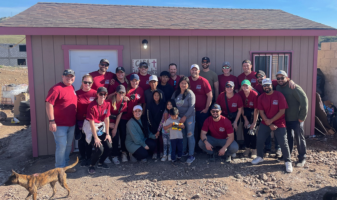 The Home Build 2023 attendees proudly pose for a picture in front of their first completed home